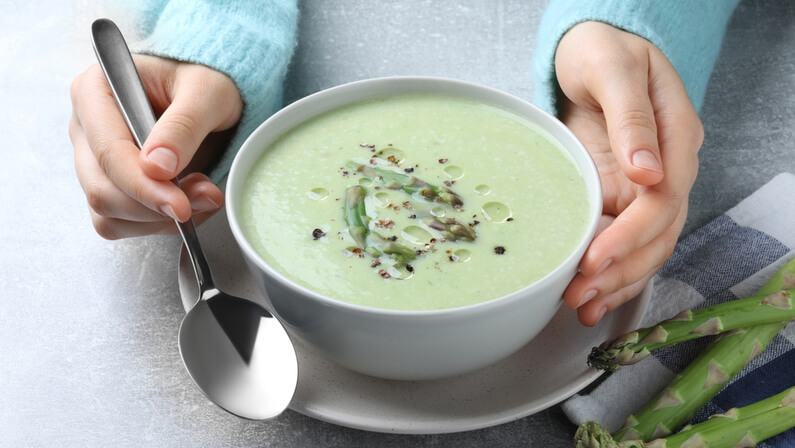 woman eating blended soup in a bowl