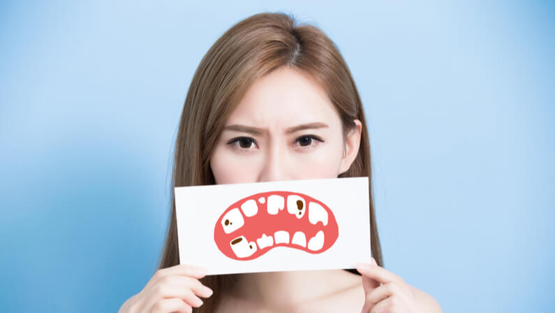 young woman holding a decay tooth photo card