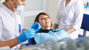 Cosmetic dentistry. Male doctor with his assistant inspecting woman patient teeth. Concept of medical staff and teamwork.