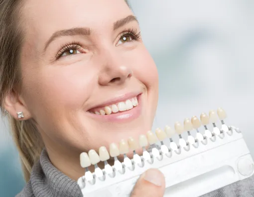 A smiling woman holds a toothbrush, ready to start her dental care routine.
