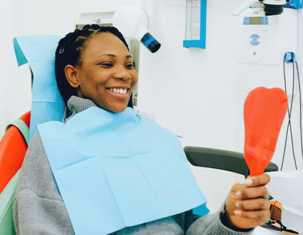 black woman looking at mirror in the dental chair