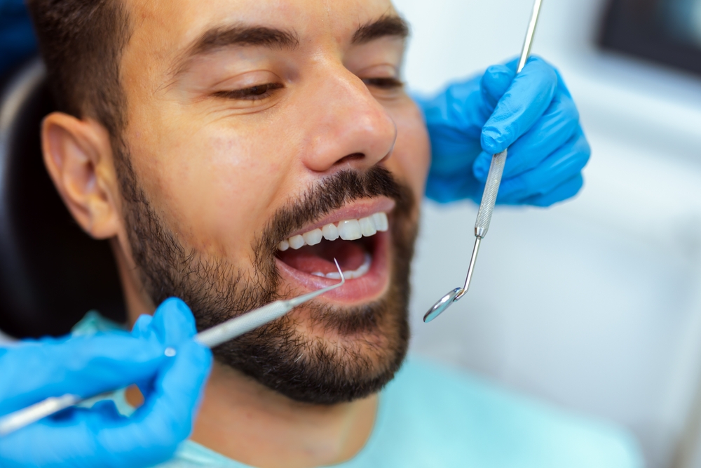 Close-up of a man with open mouth during dental checkup in modern dental clinic.