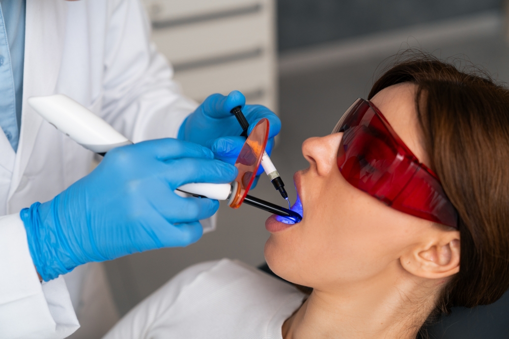 A young beautiful European brunette undergoes a teeth whitening treatment