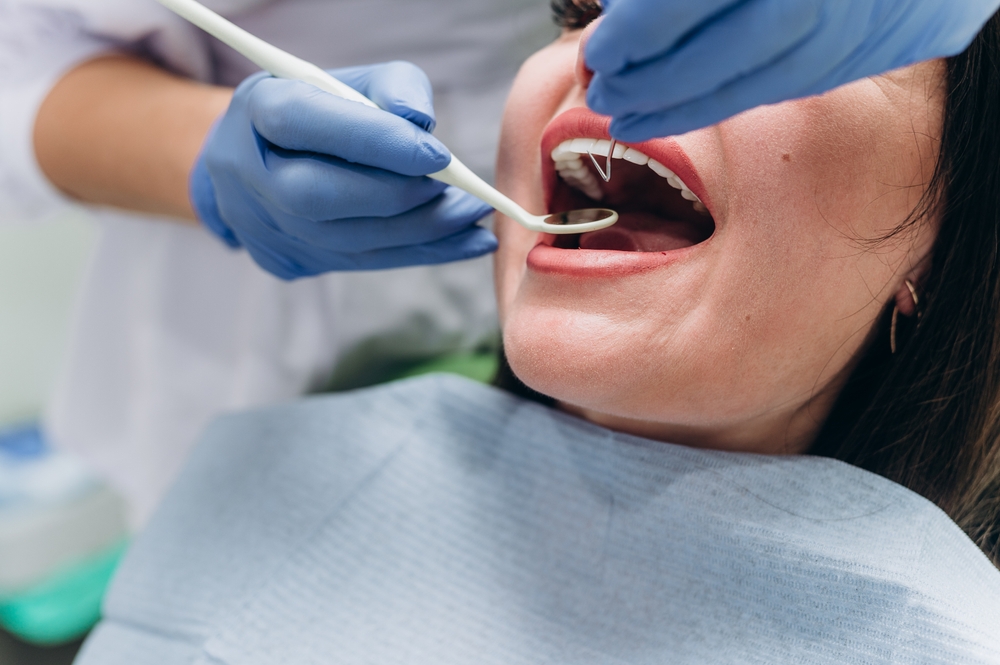 Close-up of a woman's mouth with white teeth during a dental procedure in a clinic.